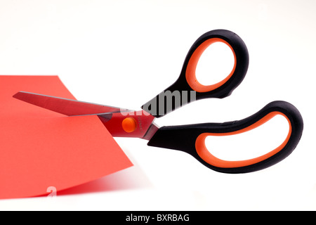 Ciseaux coupant à travers une feuille de papier rouge Banque D'Images