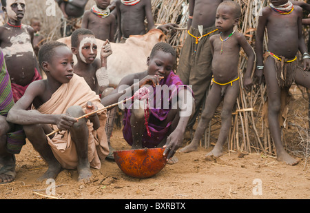 Les Nyangatom (Bumi) garçons partageant une calebasse de sang de vache, la vallée de la rivière Omo, en Ethiopie du sud Banque D'Images