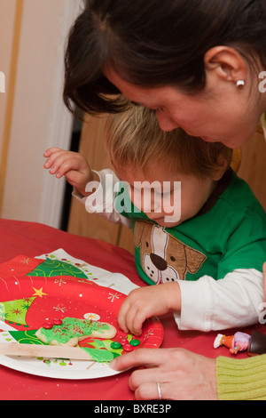 Mère mexicaine supervise son fils de deux ans de la décoration d'une cut-out cookie avec M&Ms Banque D'Images