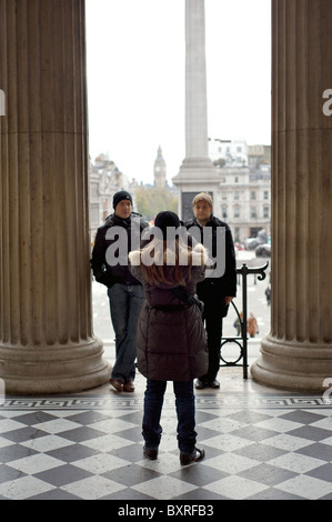 Une dame en photographiant ses deux amis à l'entrée de la Galerie Nationale avec Big Ben au loin, Londres, Angleterre Banque D'Images