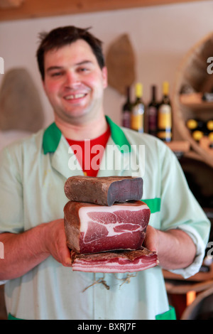 Un Boucher est titulaire d'une sélection de viandes séchées et bacon à la boucherie du Val d'Anniviers à Vissoie, Suisse Banque D'Images