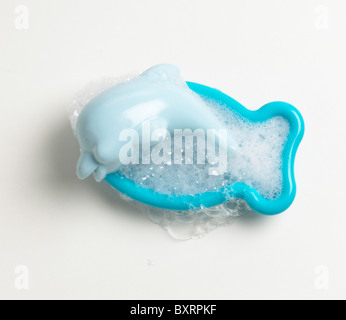 Bulles dans un plat en forme de poisson bleu avec un savon en forme de dauphin Banque D'Images