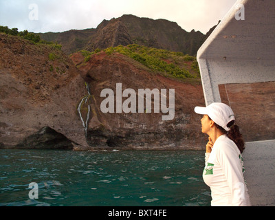 Photo de mature woman looking at waterfall sur Kauai côte de Na Pali, prises à partir de l'eau dans la lumière du matin Banque D'Images