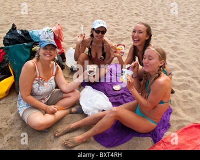 Quatre femmes eating ice cream on Kalalau beach le long de la côte de Na Pali après kayak il y a de Haena Kauai, Banque D'Images