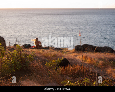 Près d'une femme, ou le site heiau ancient temple Hawaiien donnant sur l'océan au-dessus de Kalalau beach, côte de Na Pali, Kauai Banque D'Images