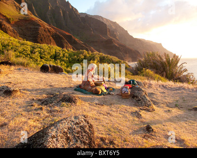 Une femme près d'un Heiau, un ancien temple hawaïen site, donnant sur l'océan au-dessus de Kalalau beach, côte de Na Pali, Kauai Banque D'Images