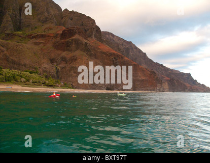 Avis de Kalalau beach et cascade à partir de l'eau tôt le matin, la lumière avec un canot et kayak à proximité, Na Pali, Kauai Banque D'Images