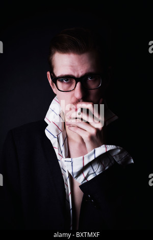 Portrait de jeune homme classique dans les verres avec la cigarette sur fond noir Banque D'Images