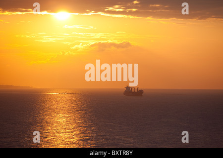 Lever du soleil au large de Malaga en Espagne avec un cargo à l'ancre. Banque D'Images