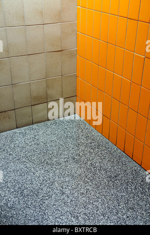 Coin d'une salle de bains publics où trois revêtements différents rencontrez, orange et beige 600x600 avec un marbre moucheté. Funky ! Banque D'Images