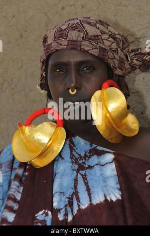 Femme demontrating Peul boucles d'or géant dans les Peul règlement de Senossa, Mali Banque D'Images