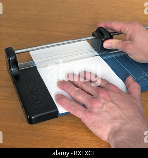 Mâle adulte de race blanche à l'aide d'un papier A4 et machine de découpe carte pour couper le papier, le modèle britannique publié Banque D'Images