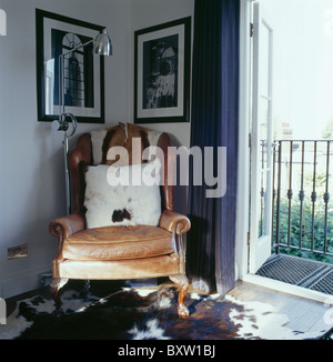 Coussin en fausse fourrure sur le vieux fauteuil en cuir dans le coin du salon à côté des portes de balcon Banque D'Images