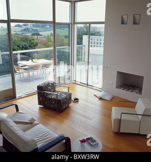 Grand séjour moderne avec des portes en verre et de baies vitrées et de chaises de chaque côté d'une cheminée moderne Banque D'Images