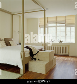 Tabourets tissu crème carrés au pied du lit à baldaquin moderne dans des tons crème chambre avec parquet au sol et la crème , blinds Banque D'Images