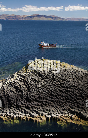 Staffa bateau d'excursion et de basalte polygonal, suis Buachaille rocks, Staffa, au large de l'île de Mull (à distance), Ecosse, Royaume-Uni Banque D'Images