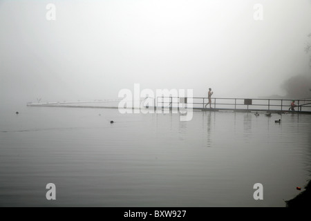 Nageur qui sortent d'une Serpentine Lido misty dans Hyde Park, Londres, UK Banque D'Images