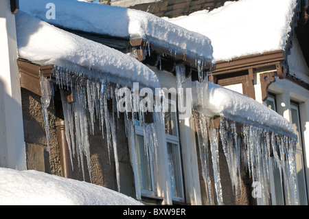 De Glaçons pendant le toit d'une maison en hiver Banque D'Images