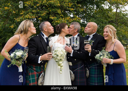 Close up portrait of horizontal d'une bride and groom kissing avec leurs meilleurs hommes et de demoiselles tacaud et imiter. Banque D'Images