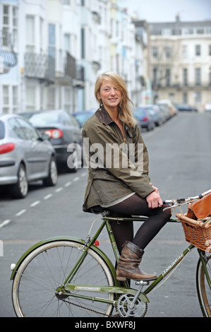 Young blonde woman riding bicycle avec panier road Brighton UK Banque D'Images
