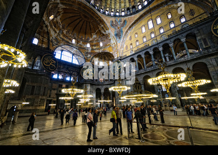 ISTANBUL, Turquie — le vaste hall principal de la basilique Sainte-Sophie présente son remarquable design architectural byzantin, avec son massif dôme central soutenu par des pendentifs et des semi-dômes. L'intérieur présente à la fois des éléments chrétiens et islamiques, y compris des mosaïques byzantines, de la calligraphie ottomane et de grands avize ottomans (lustres). D'énormes colonnes et panneaux de marbre bordent l'espace, démontrant la grandeur de l'ingénierie architecturale du vie siècle. Banque D'Images