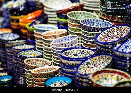 Assiettes en céramique Grand Bazaar Istanbul Turquie | ISTANBUL, Turquie — Des bols en céramique peints de couleurs vives empilés en hautes colonnes arborent des motifs floraux et géométriques dans une boutique du Grand Bazaar. Le style de poterie est enraciné dans la tradition céramique d'Iznik qui a prospéré sous le patronage ottoman à partir du XVe siècle et reste l'une des catégories de marchandises les plus populaires du bazar. Le marché fait partie des zones historiques d'Istanbul inscrites sur la liste du patrimoine mondial de l'UNESCO en 1985. Banque D'Images