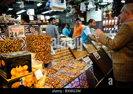 Epicerie du Bazaar aux épices et sucreries Istanbul Turquie | ISTANBUL, Turquie — Des plateaux de lokum aux pistachios et de fruits secs garnissent l’étal d’un vendeur dans le Bazaar aux épices, également appelé le Bazaar Égyptien ou Mısır Çarşısı. Construit au début des années 1660 comme annexe commerciale du complexe Yeni Cami, le marché a cédé environ la moitié de ses boutiques d’origine à des herboristes-apothicaires ; aujourd’hui, les confiseries, les noix et le Turkish delight restent des piliers de son commerce. Banque D'Images