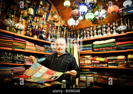 ISTANBUL, Turquie / Türkiye — le vendeur montre quelques-uns de ses foulards en soie dans son magasin du bazar Arastar, un petit bazar à côté du Sultanahment Camii (Mosquée bleue) à Istanbul, en Turquie. Banque D'Images