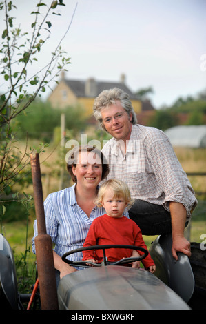 Une famille sur leurs lopins de terre avec un vieux tracteur et polytunnel fleurs ferme commune UK Banque D'Images