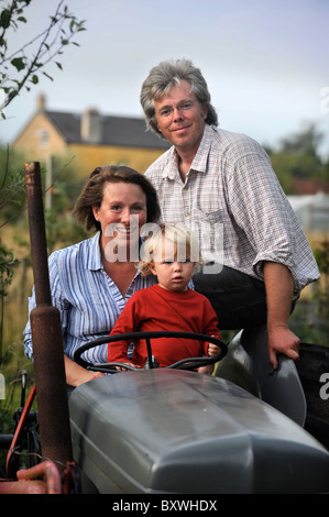 Une famille sur leurs lopins de terre avec un vieux tracteur et polytunnel fleurs ferme commune UK Banque D'Images