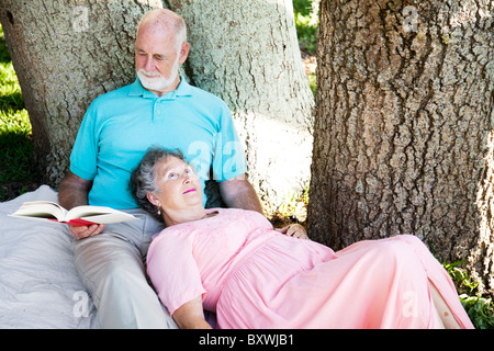 Man se lit à sa femme, vous détendre dans le parc. Banque D'Images