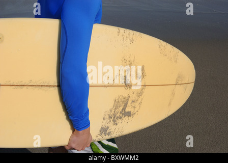 Surfer sur la plage dans l'océan avec son conseil. Banque D'Images