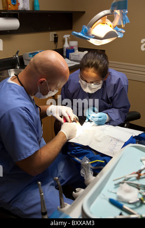 Anglo male dentist travaille sur patient tandis que les femmes assistant dentaire ressemble sur dans la salle de traitement d'une clinique dentaire à Austin TX USA Banque D'Images