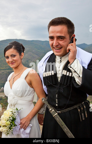 Mariée de style géorgien avec époux en costume national sur téléphone cellulaire au 6ème siècle de l'Église de Jvari sur Sagurami Hills, Georgia. JMH4114 Banque D'Images