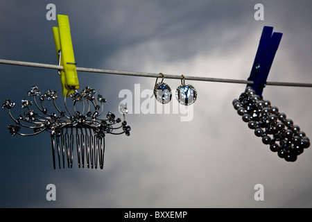 Bijoux élégant accrochées sur un fil à linge avec pinces à linge colorées et ciel d'orage. Banque D'Images