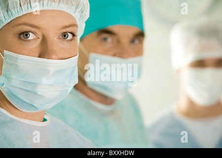 Portrait of female surgeon wearing masque de protection sur l'arrière-plan de ses collègues Banque D'Images