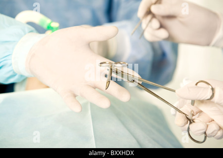 Close-up of main gantée de chirurgien adjoint de l'instrument en tenant Banque D'Images