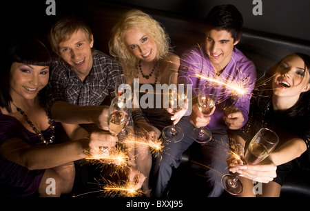 Vue de dessus d'amis joyeux avec champagne et des lumières scintillantes dans les mains pendant la célébration Banque D'Images