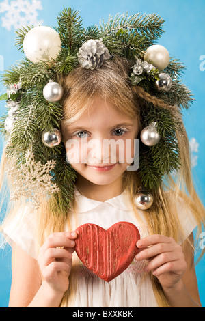 Portrait de belle fille portant des décorations de Noël sur la tête et mains en coeur rouge holding Banque D'Images