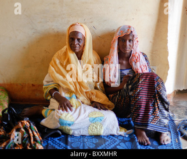 Un vieux et jeune femme s'asseoir ensemble sur un tapis dans une maison à Ouagadougou, Burkina Faso. Banque D'Images