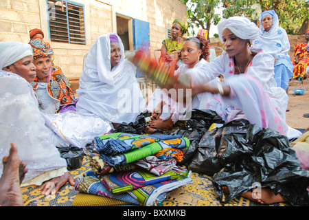 À Ouagadougou, Burkina Faso, les femmes apportent des dons de vêtements à l'enfant un baptême. Banque D'Images