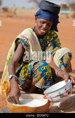 Une femme peule lait dans une calebasse en vente dans le marché hebdomadaire de Djibo dans le nord du Burkina Faso. Banque D'Images