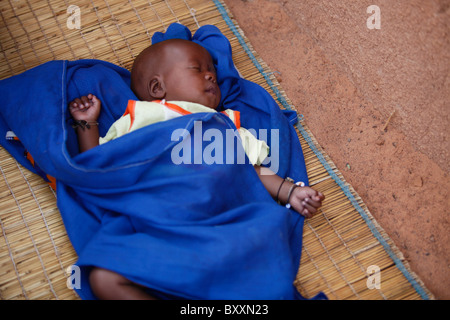 Un bébé dort sur un matelas de paille sur le sol à Djibo dans le nord du Burkina Faso. Banque D'Images