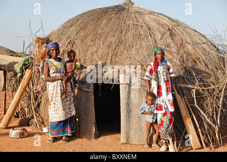 Dans le village peul de Jolooga dans le nord du Burkina Faso, les villageois se tiennent à l'extérieur d'une maison traditionnelle faite à partir de la paille. Banque D'Images