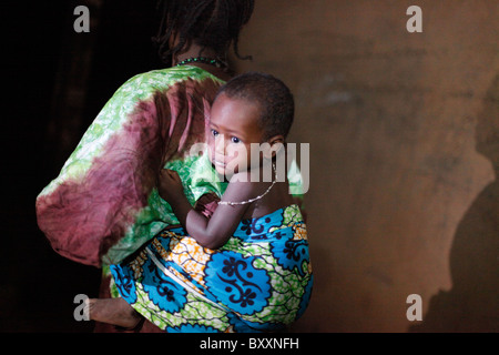 Comme la nuit tombe sur la ville de Djibo, au nord du Burkina Faso, une femme à son enfant bretelles dos. Banque D'Images