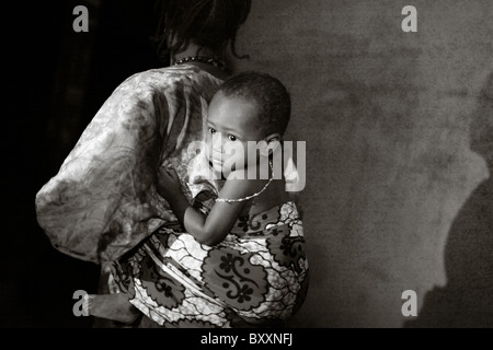 Comme la nuit tombe sur la ville de Djibo, au nord du Burkina Faso, une femme à son enfant bretelles dos. Banque D'Images