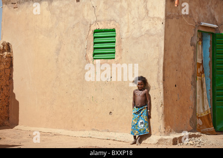 Une jeune fille se tient Peuls contre une maison de terre dans la ville de Djibo dans le nord du Burkina Faso. Banque D'Images