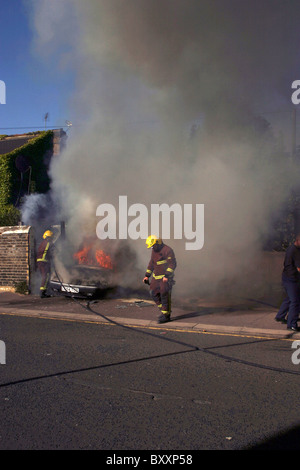 Pompiers lutter contre une voiture en feu Banque D'Images