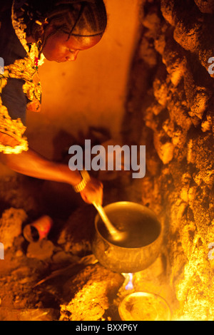 Une femme à Djibo, Burkina Faso cuisiniers millet, 'pot' similaire à la polenta Italienne sur un feu en plein air. Banque D'Images