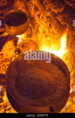 Une femme à Djibo, Burkina Faso cuisiniers millet, 'pot' similaire à la polenta Italienne sur un feu en plein air. Banque D'Images